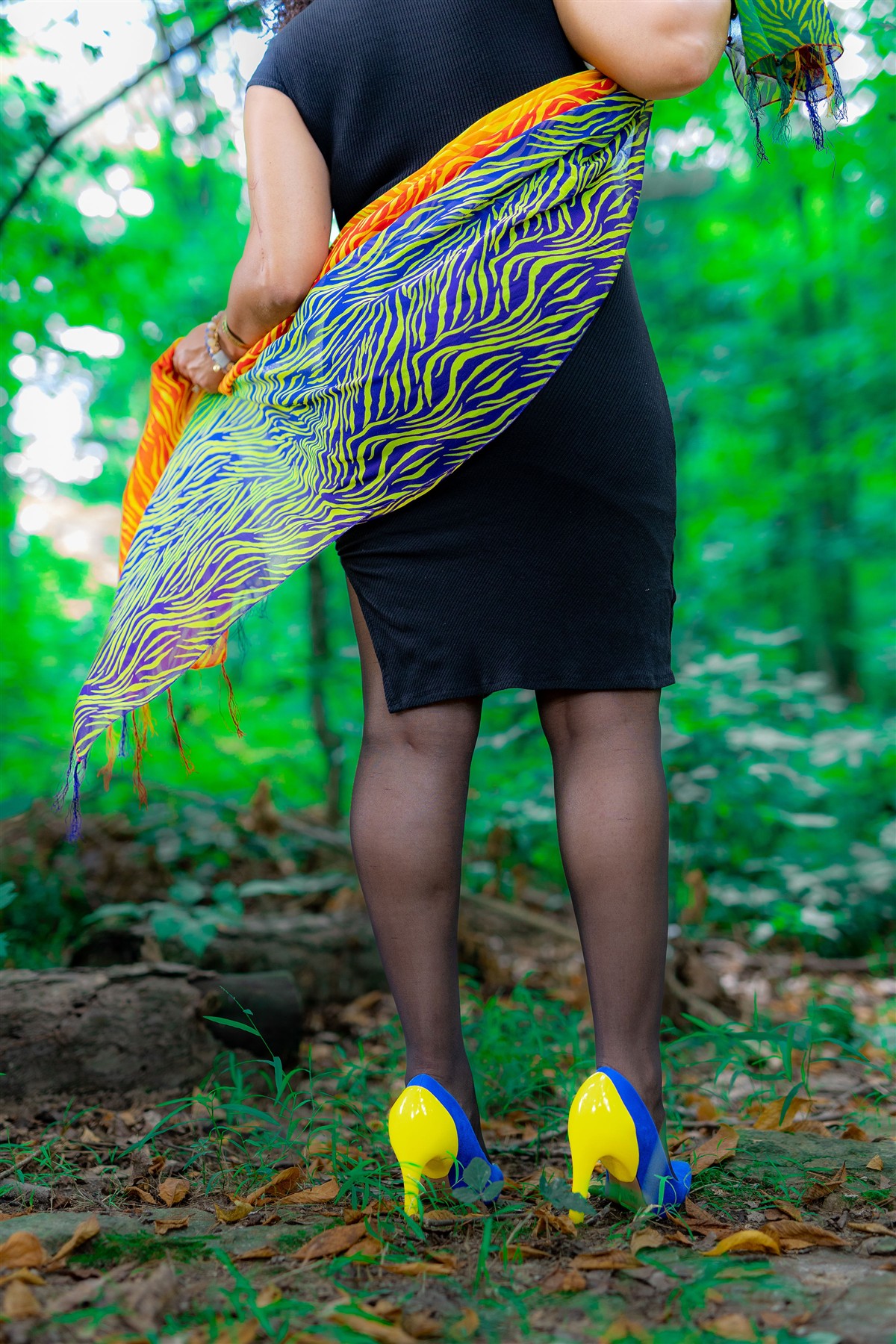 Model wearing a patterned skirt and bright heel covers outdoors