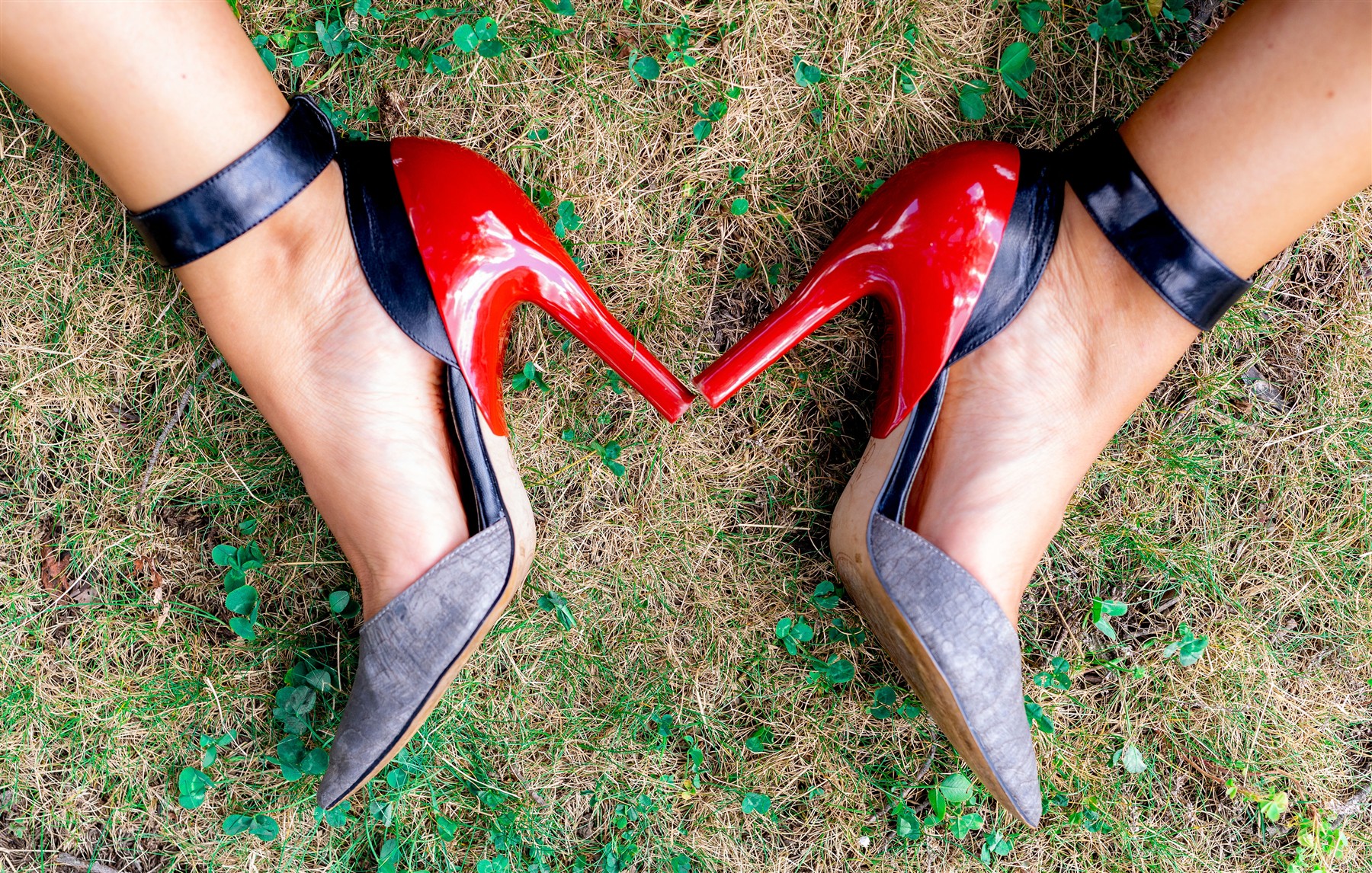 Two nude slim high heels with red heel covers on grass